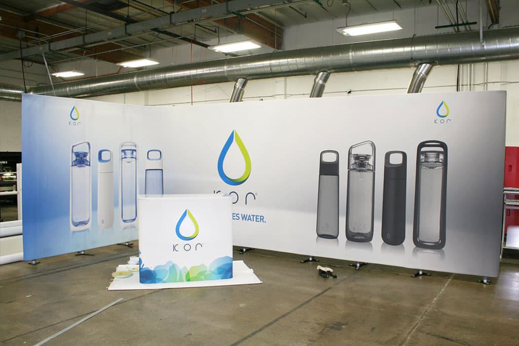 Kor tensioned fabric exhibition display stand A Kor tensioned fabric exhibition display stand showcasing water bottles and a sign