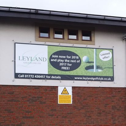 A digitally printed PVC banner with an eyelet bungee system, displayed on a building as a large billboard.