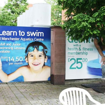 Manchester Aquatic Centre Training Camp boy wearing swimming goggles advertisement digitally printed PVC banners fixed to a fence