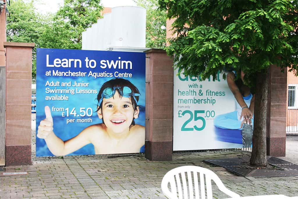 Manchester Aquatic Centre Training Camp digitally printed PVC banners fixed Manchester Aquatic Centre Training Camp boy wearing swimming goggles advertisement digitally printed PVC banners fixed to a fence