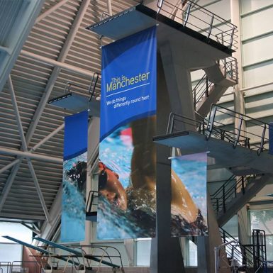 A large swimming pool with a diving board at Manchester Aquatic Centre Training Camp showcasing three digitally printed PVC banners