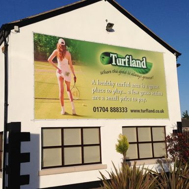 Turfland digitally printed gable PVC banner showcasing a tennis court advertisement on a building