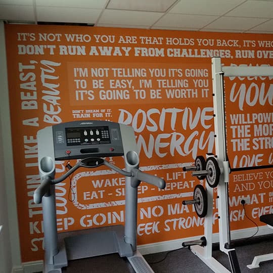 Gym room featuring wall with motivational wallpaper graphic quotes
